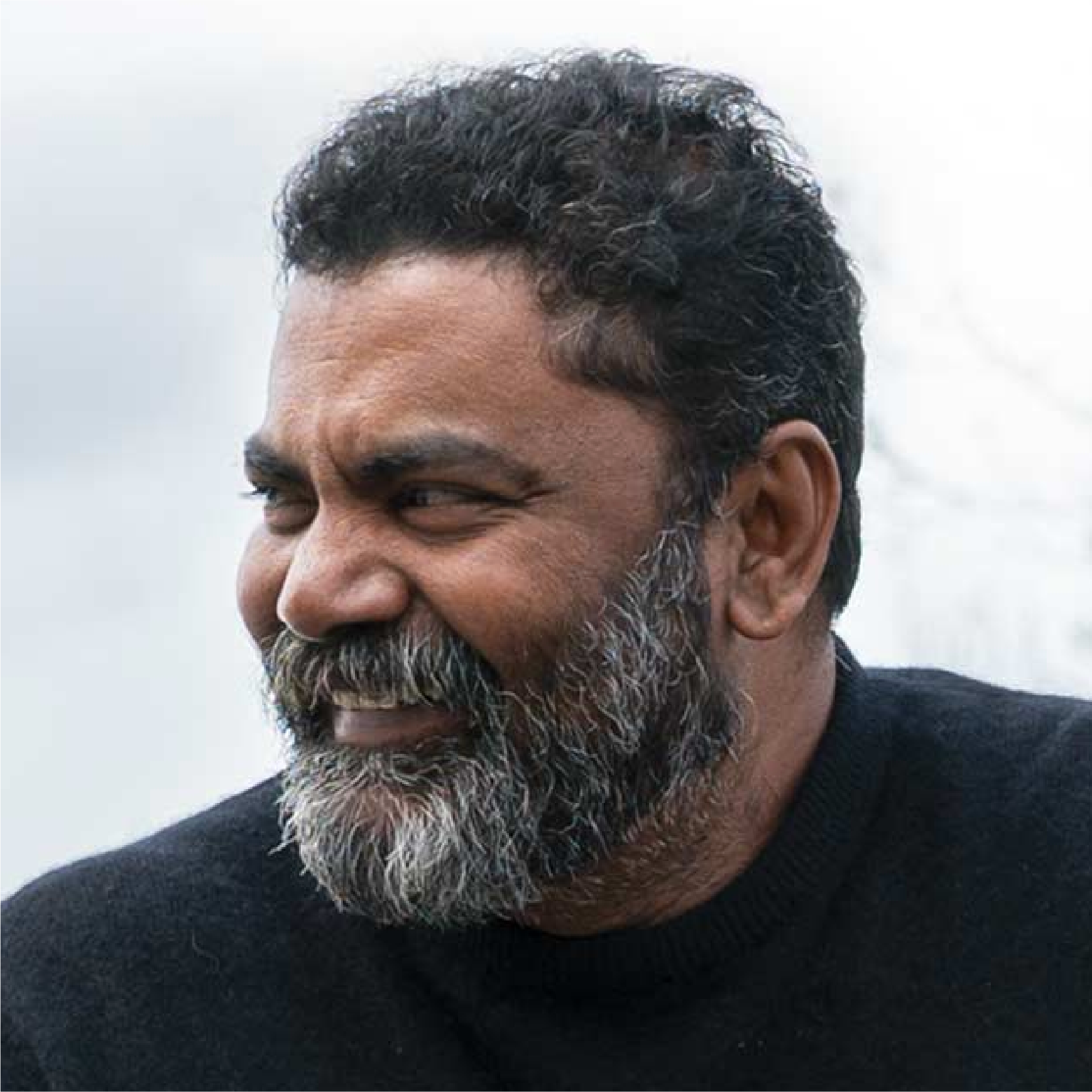 A candid photo of a bearded man smiling warmly in a black sweater. The image reflects the grounded presence and inner ease that re:you often speaks to—this is a real moment, not a pose.